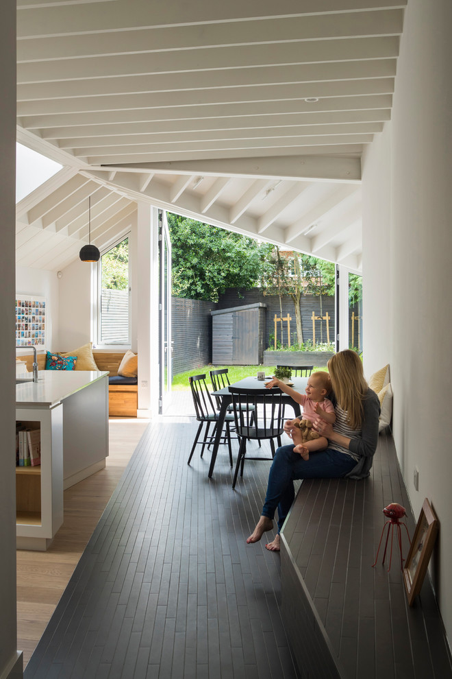 Contemporary kitchen/dining room in London with white walls, porcelain flooring and black floors.