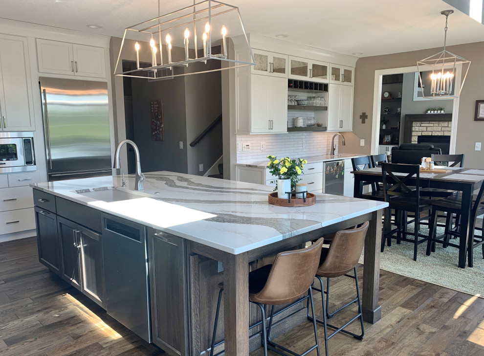 Large classic l-shaped kitchen/diner in Other with a submerged sink, flat-panel cabinets, white cabinets, engineered stone countertops, multi-coloured splashback, engineered quartz splashback, stainless steel appliances, medium hardwood flooring, an island, grey floors and multicoloured worktops.