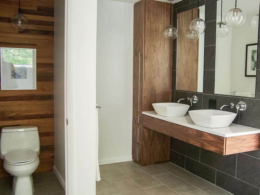 Mid-sized modern master bathroom in Grand Rapids with gray tile, quartzite benchtops, flat-panel cabinets, medium wood cabinets, a freestanding tub, a one-piece toilet, ceramic tile, ceramic floors, a vessel sink and multi-coloured walls.
