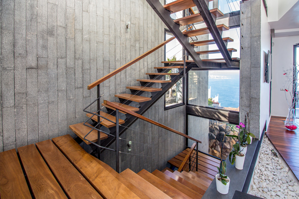Design ideas for a contemporary wood u-shaped staircase in Other with open risers and cable railing.