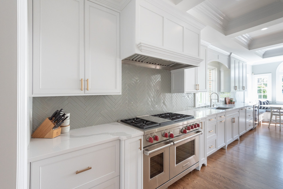 Design ideas for a large beach style u-shaped eat-in kitchen in Providence with an undermount sink, shaker cabinets, white cabinets, quartz benchtops, white splashback, glass tile splashback, panelled appliances, dark hardwood floors, with island, brown floor and white benchtop.