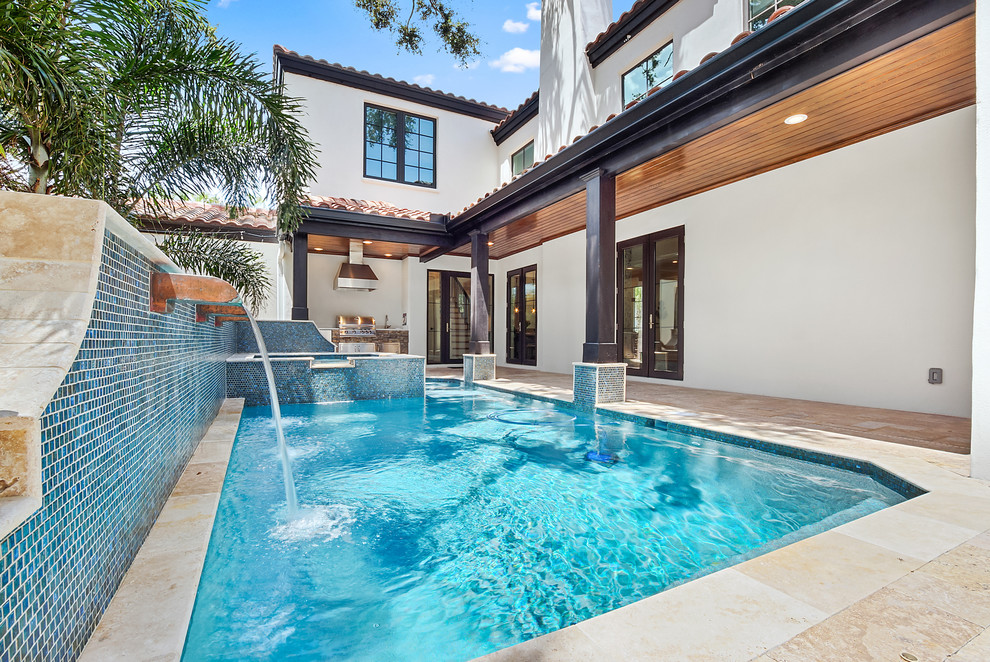 This is an example of a mediterranean backyard rectangular lap pool in Tampa with a water feature.