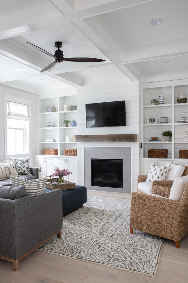 Design ideas for a large country enclosed family room in Chicago with white walls, light hardwood floors, a standard fireplace, a tile fireplace surround, a wall-mounted tv and beige floor.