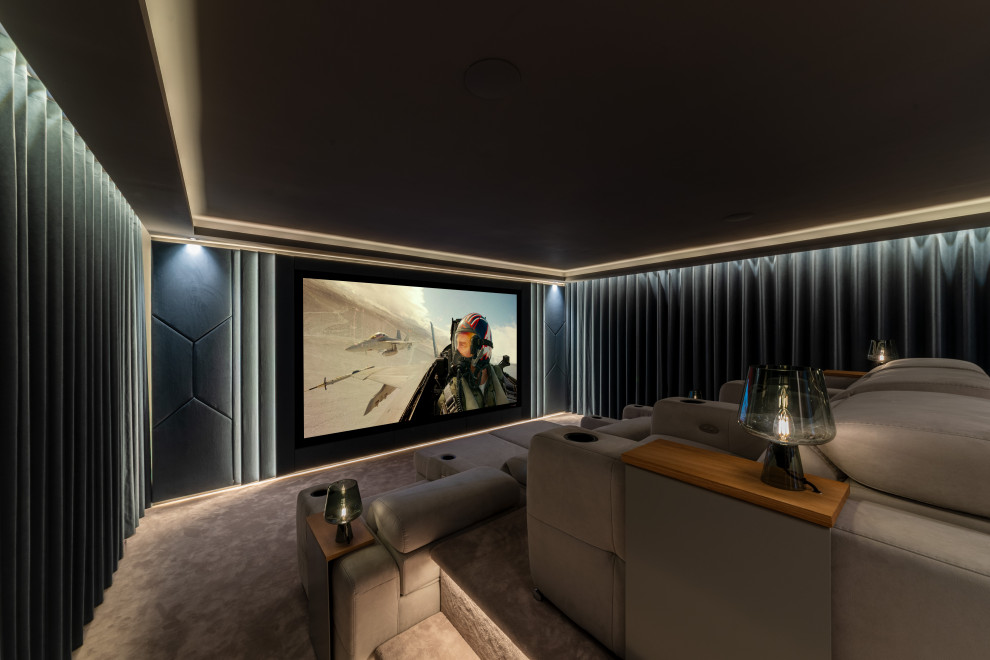 Photo of a mid-sized enclosed home theatre in Kent with grey walls, carpet, a projector screen and grey floor.
