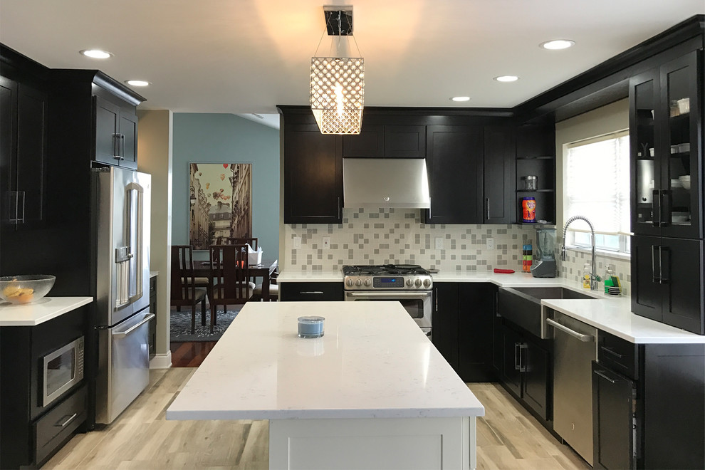 Inspiration for a mid-sized transitional l-shaped light wood floor and beige floor enclosed kitchen remodel in Bridgeport with a farmhouse sink, shaker cabinets, dark wood cabinets, quartz countertops, stainless steel appliances, an island, white backsplash and glass tile backsplash