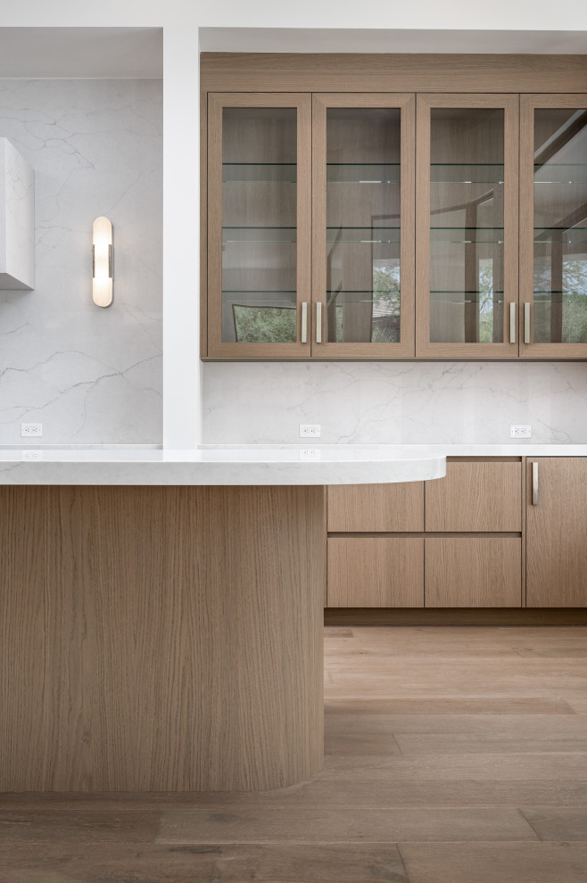 Design ideas for a modern kitchen in Phoenix with medium wood cabinets, quartz benchtops, engineered quartz splashback, medium hardwood floors and glass-front cabinets.