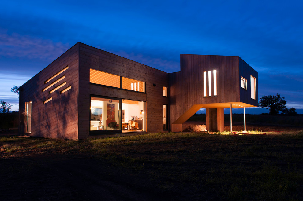 Photo of a large contemporary two-storey brown house exterior in Lyon with wood siding and a flat roof.