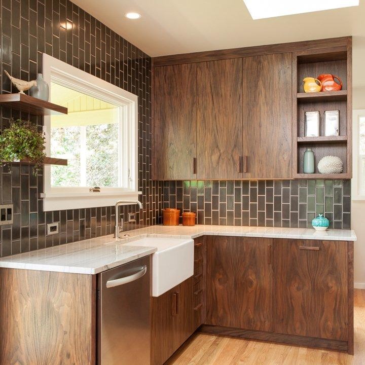 Inspiration for a midcentury separate kitchen in Portland with a farmhouse sink, flat-panel cabinets, dark wood cabinets, quartzite benchtops, black splashback, ceramic splashback, stainless steel appliances and light hardwood floors.