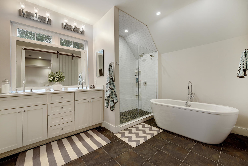 This is an example of a transitional bathroom in Austin with shaker cabinets, white cabinets, a freestanding tub, a corner shower, white tile, subway tile, white walls and a hinged shower door.