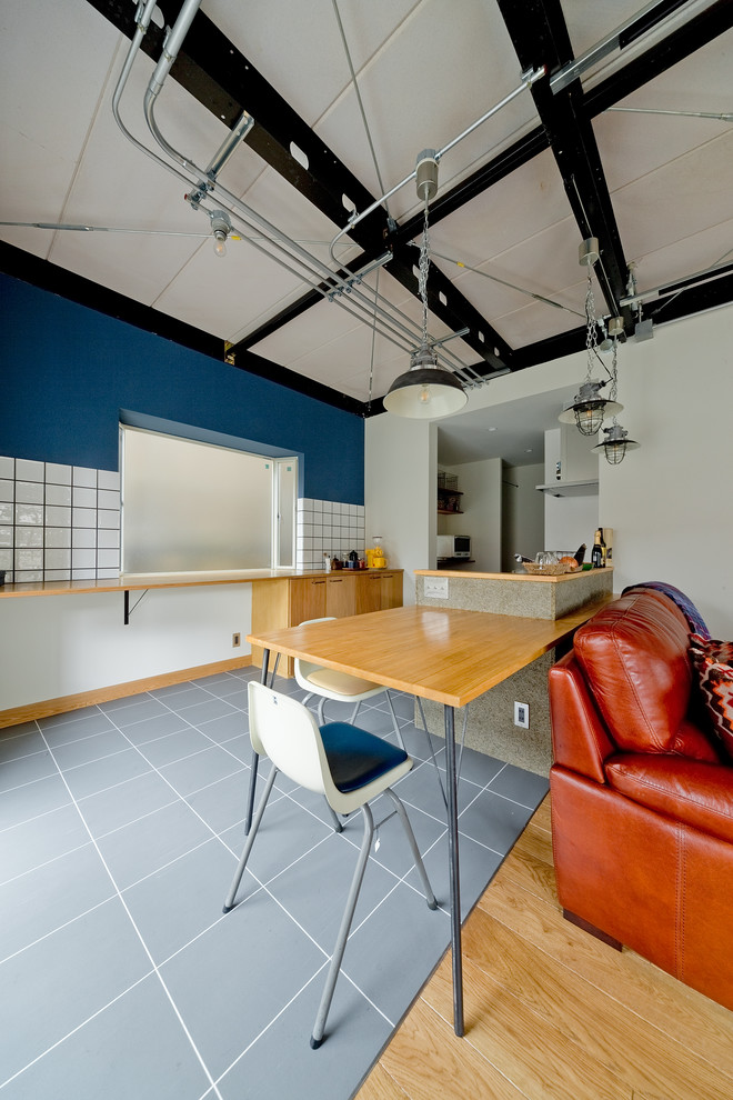 This is an example of an industrial open plan dining in Osaka with blue walls, no fireplace and grey floor.