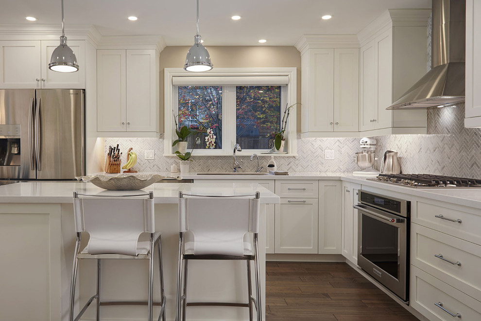Inspiration for a mid-sized transitional l-shaped brown floor and dark wood floor eat-in kitchen remodel with shaker cabinets, white cabinets, gray backsplash, stainless steel appliances and an island
