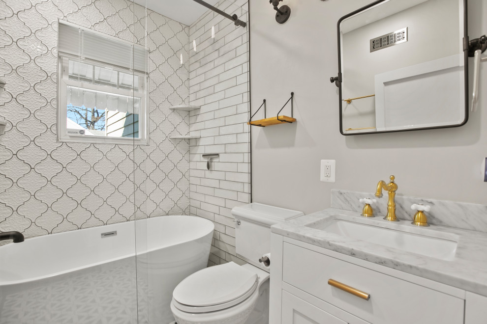 На фото: маленькая главная ванная комната в стиле ретро с плоскими фасадами, белыми фасадами, отдельно стоящей ванной, душем над ванной, унитазом-моноблоком, белой плиткой, керамической плиткой, серыми стенами, паркетным полом среднего тона, накладной раковиной, столешницей из искусственного кварца, коричневым полом, душем с раздвижными дверями, серой столешницей, тумбой под одну раковину и напольной тумбой для на участке и в саду с