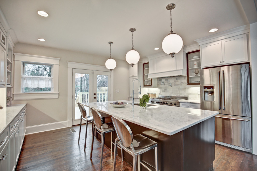 Photo of a mid-sized arts and crafts u-shaped eat-in kitchen in Atlanta with an undermount sink, shaker cabinets, white cabinets, marble benchtops, grey splashback, stone tile splashback, stainless steel appliances, dark hardwood floors, with island and brown floor.