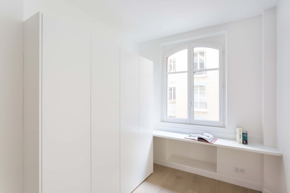 Photo of a contemporary storage and wardrobe in Paris with light hardwood floors.