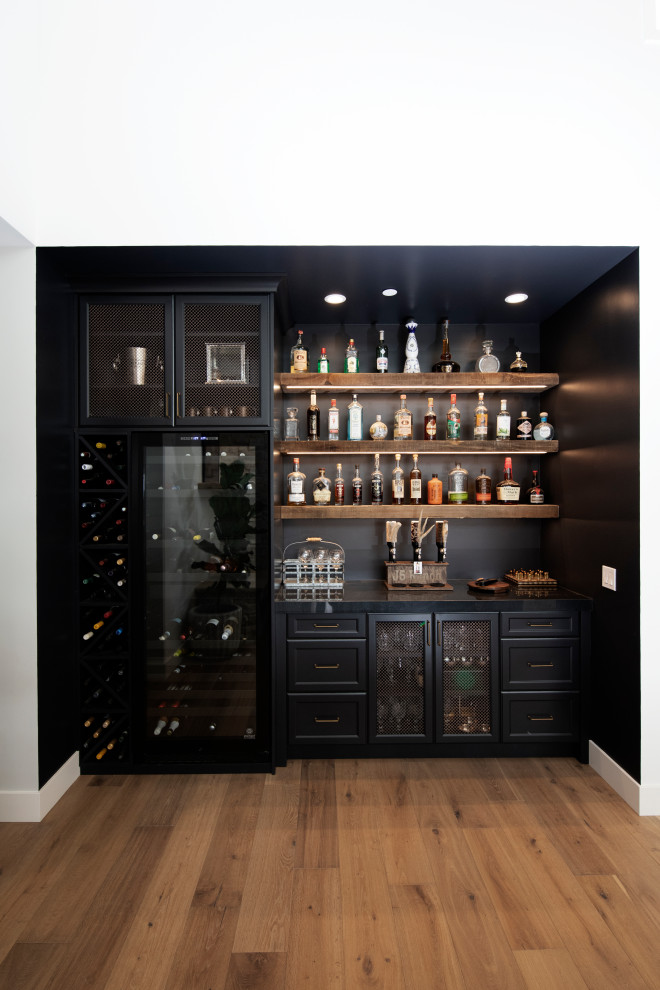 Einzeilige, Kleine Moderne Hausbar mit trockener Bar, Schrankfronten mit vertiefter Füllung, schwarzen Schränken, Granit-Arbeitsplatte, Küchenrückwand in Schwarz, braunem Holzboden und schwarzer Arbeitsplatte in San Diego