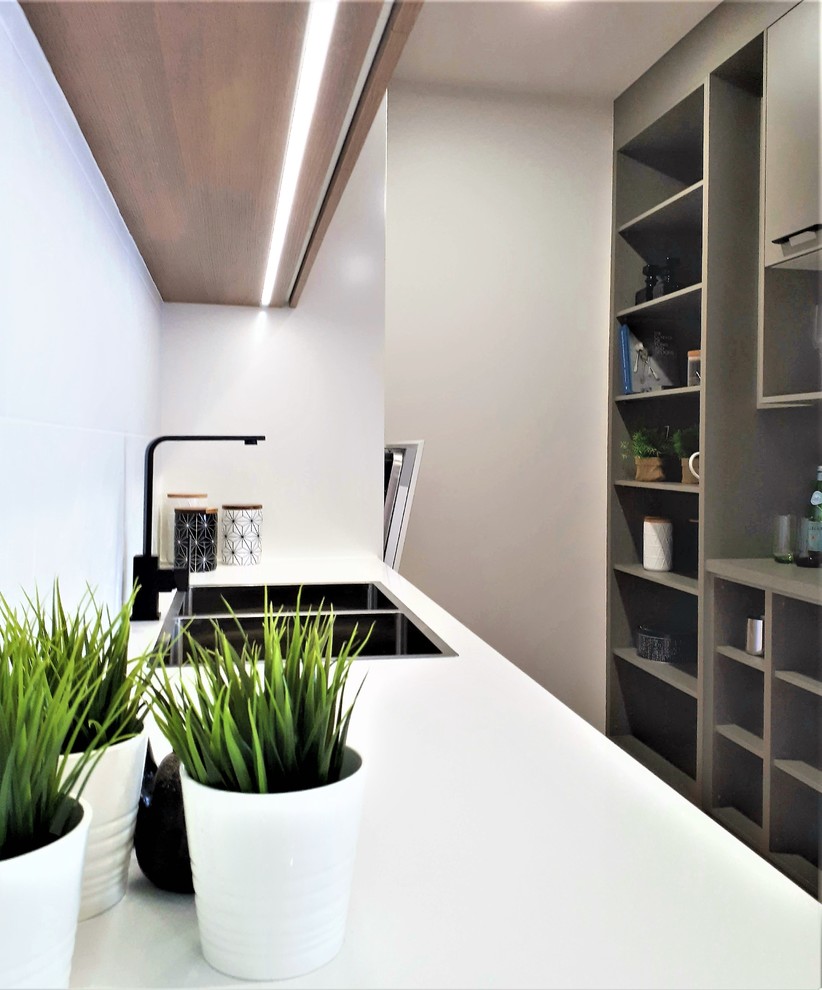 Inspiration for a large scandinavian galley kitchen pantry with a drop-in sink, flat-panel cabinets, medium wood cabinets, quartz benchtops, white splashback, ceramic splashback, black appliances, multiple islands and white benchtop.