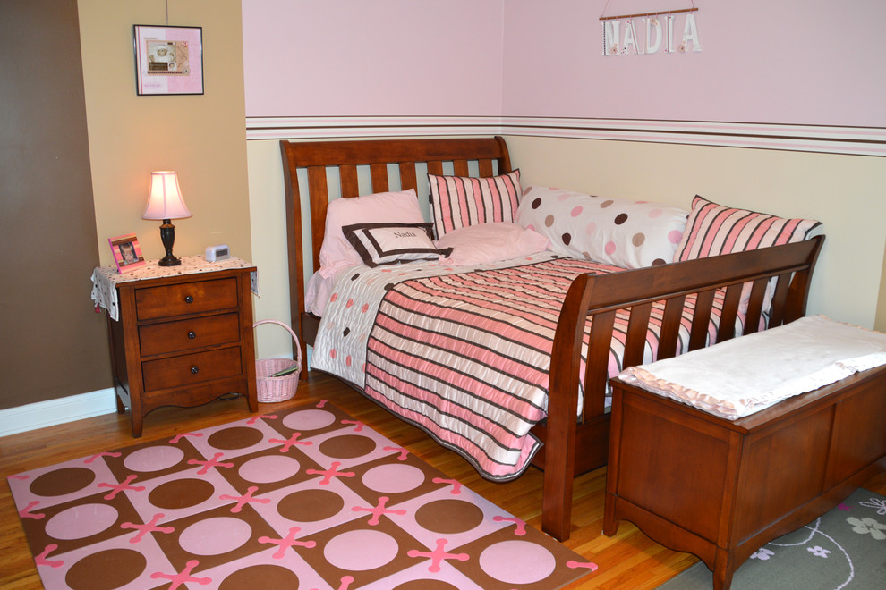 Photo of a traditional kids' room for kids 4-10 years old and girls in Minneapolis with pink walls and medium hardwood floors.