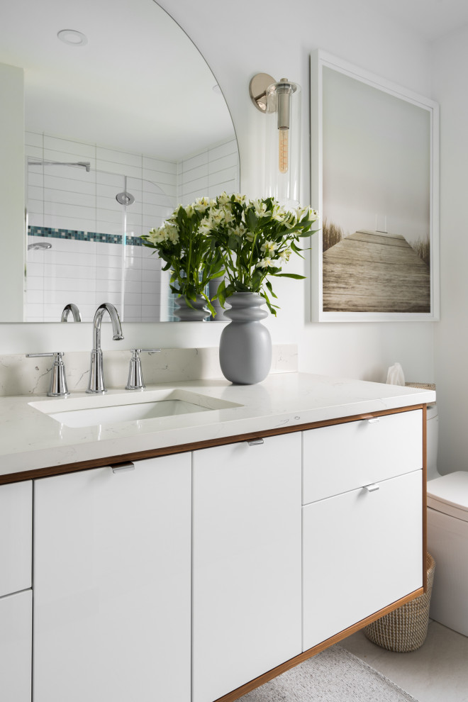 This is an example of a mid-sized contemporary kids bathroom in Montreal with flat-panel cabinets, white cabinets, an alcove tub, an alcove shower, a one-piece toilet, white tile, ceramic tile, white walls, ceramic floors, an undermount sink, quartzite benchtops, beige floor, a hinged shower door, white benchtops, a single vanity and a floating vanity.