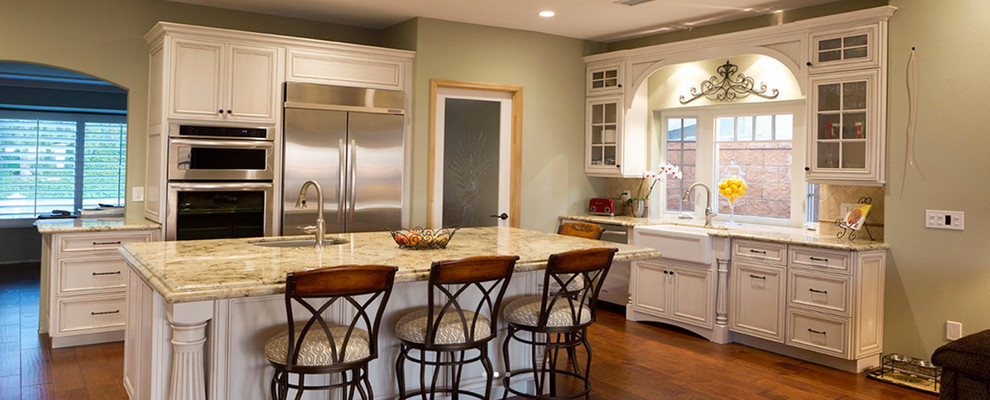 Inspiration for a large transitional u-shaped dark wood floor and brown floor open concept kitchen remodel in Houston with a farmhouse sink, beaded inset cabinets, white cabinets, granite countertops, beige backsplash, stone tile backsplash, stainless steel appliances and an island