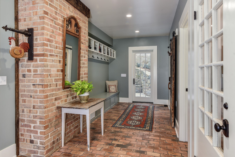 Mid-sized country mudroom in Other with grey walls, brick floors, a single front door and a glass front door.