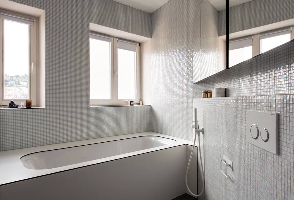 Photo of a small modern bathroom in Milan with glass-front cabinets, an undermount tub, a wall-mount toilet, green tile, mosaic tile, green walls, mosaic tile floors and a console sink.
