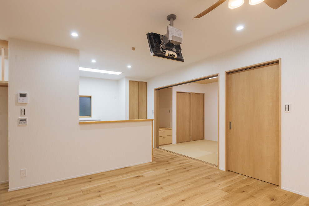 他の地域にある中くらいな北欧スタイルのおしゃれなLDK (白い壁、淡色無垢フローリング、ベージュの床、クロスの天井、壁紙) の写真
