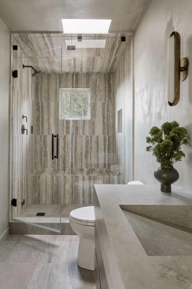 Inredning av ett modernt litet grå grått badrum, med släta luckor, bruna skåp, en hörndusch, flerfärgad kakel, travertinkakel, grå väggar, betonggolv, ett integrerad handfat, bänkskiva i betong, grått golv och dusch med gångjärnsdörr