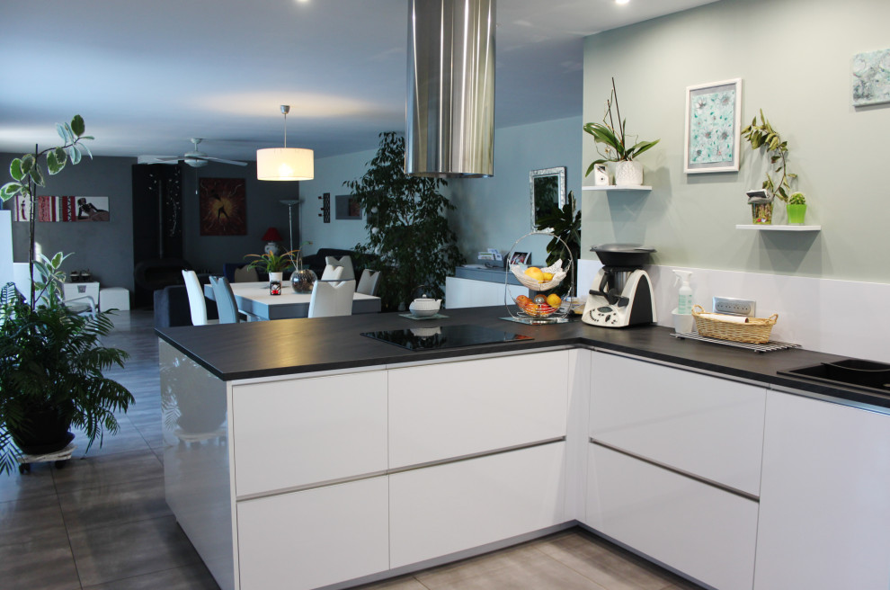 Mid-sized contemporary u-shaped open plan kitchen in Other with a drop-in sink, white cabinets, laminate benchtops, white splashback, stainless steel appliances, ceramic floors, with island, black benchtop and grey floor.