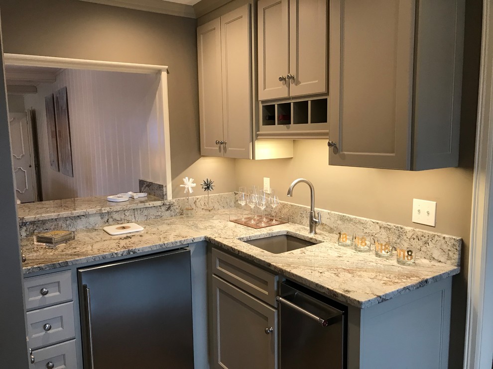 This is an example of a small transitional l-shaped wet bar in Other with an undermount sink, shaker cabinets, grey cabinets, granite benchtops, grey splashback, light hardwood floors and grey floor.
