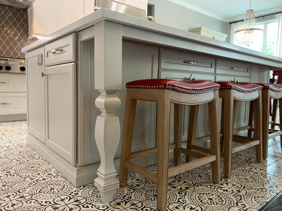 Inspiration for a transitional l-shaped porcelain tile and multicolored floor kitchen remodel in Houston with a farmhouse sink, recessed-panel cabinets, white cabinets, quartz countertops, gray backsplash, ceramic backsplash, stainless steel appliances, an island and white countertops
