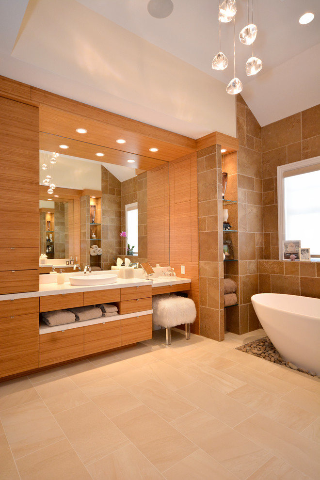 Photo of a large modern master bathroom in New York with flat-panel cabinets, medium wood cabinets, a freestanding tub, an alcove shower, a one-piece toilet, beige tile, travertine, beige walls, porcelain floors, a vessel sink, glass benchtops, beige floor and a hinged shower door.