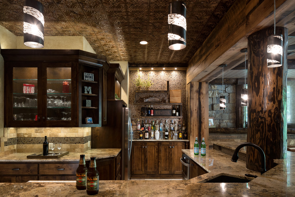 Inspiration for a large country l-shaped seated home bar in Kansas City with an undermount sink, recessed-panel cabinets, dark wood cabinets, granite benchtops, brown splashback, mosaic tile splashback and porcelain floors.