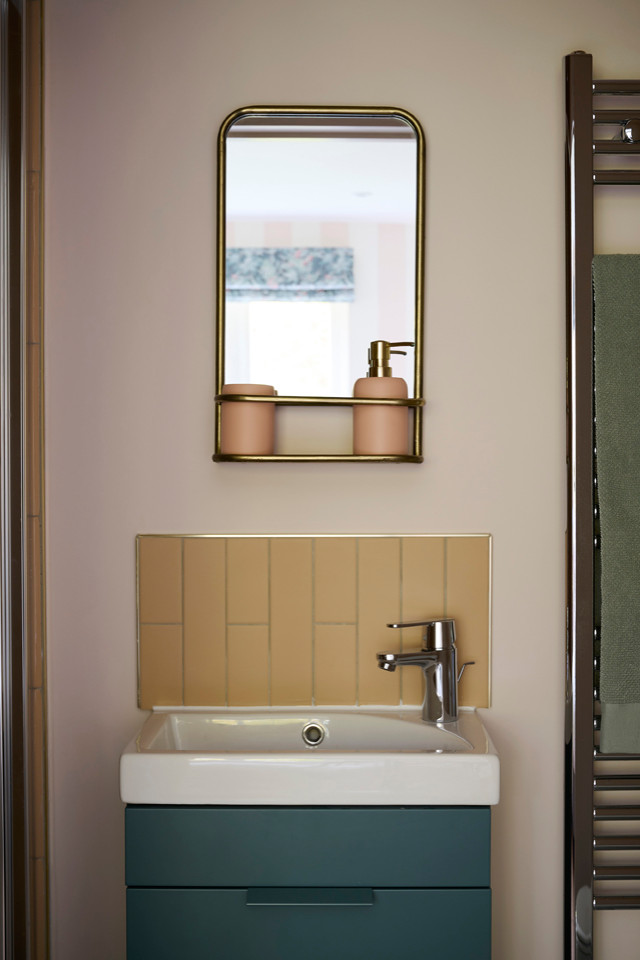 Minimalistisk inredning av ett litet badrum, med släta luckor, gröna skåp, en dusch i en alkov, en toalettstol med separat cisternkåpa, rosa kakel, rosa väggar, klinkergolv i keramik, ett integrerad handfat, grönt golv och dusch med gångjärnsdörr