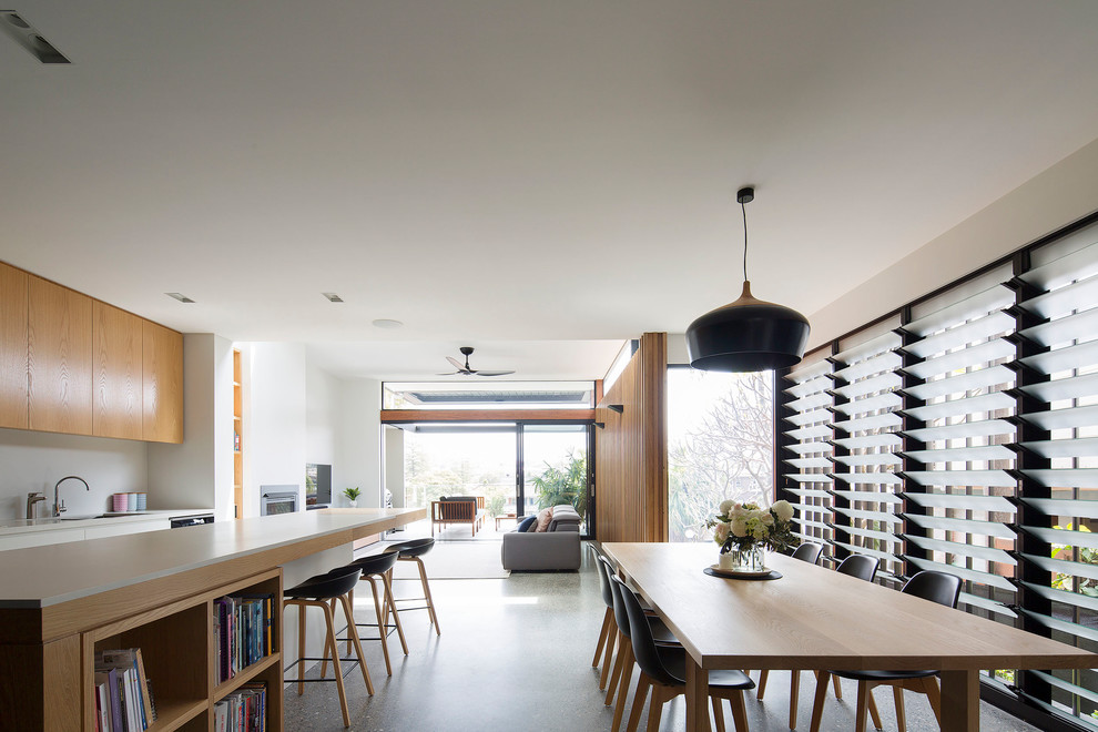 Large contemporary open plan dining in Sydney with white walls, concrete floors, a standard fireplace, a metal fireplace surround and grey floor.