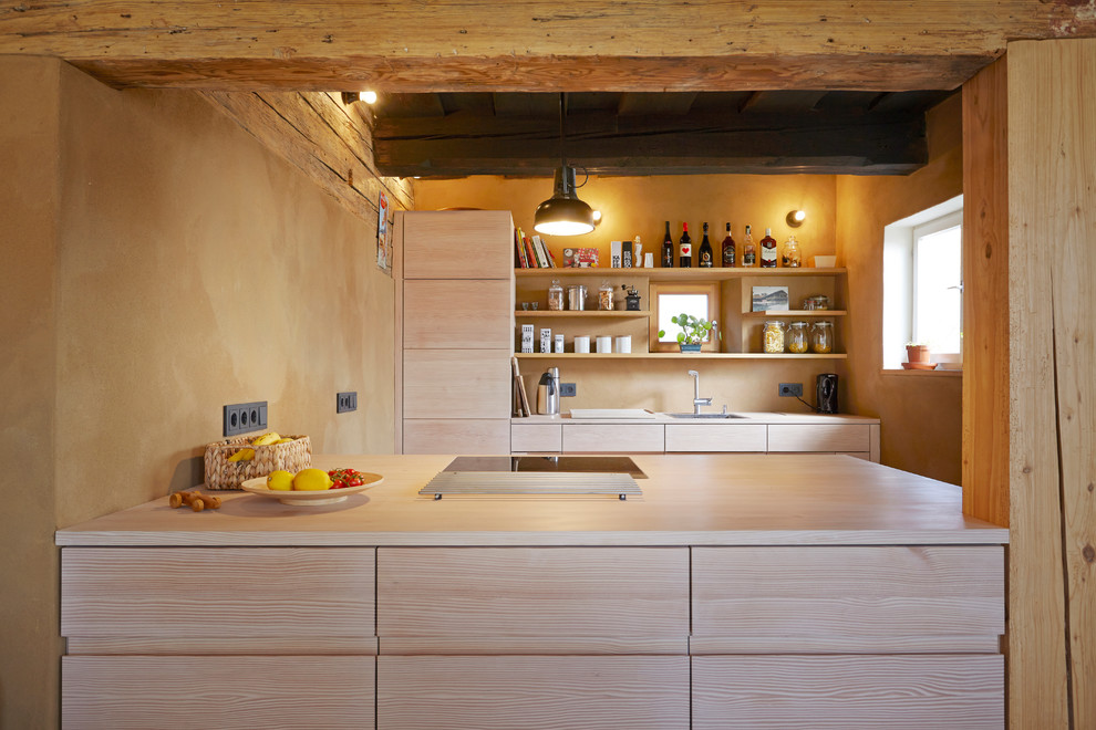 This is an example of a small country single-wall kitchen in Munich with flat-panel cabinets, medium wood cabinets, wood benchtops, beige splashback and with island.