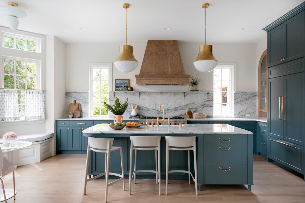 Inspiration for an expansive classic open plan kitchen in Minneapolis with a belfast sink, recessed-panel cabinets, blue cabinets, grey splashback, integrated appliances, light hardwood flooring, an island, white worktops, quartz worktops and stone slab splashback.