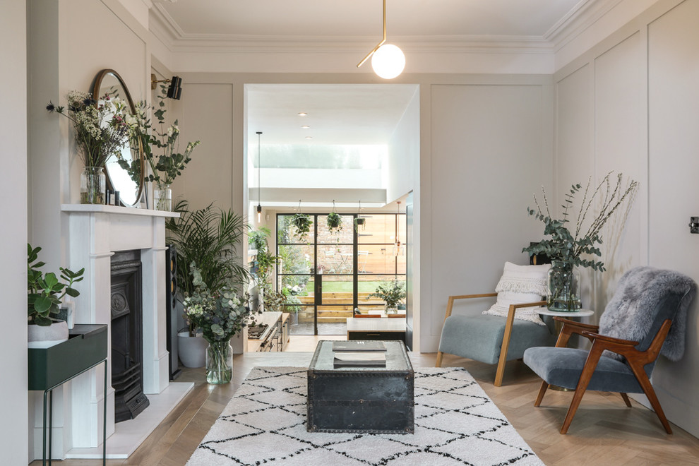 This is an example of a large scandinavian open plan living room in London with white walls, medium hardwood flooring, a standard fireplace and a stone fireplace surround.