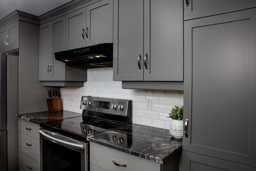 Inspiration for a gray floor kitchen remodel in Toronto with shaker cabinets, gray cabinets, white backsplash, subway tile backsplash, stainless steel appliances, an island and black countertops