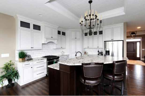 Example of a large transitional l-shaped vinyl floor and brown floor eat-in kitchen design in Cedar Rapids with recessed-panel cabinets, white cabinets, granite countertops, white backsplash, ceramic backsplash and an island