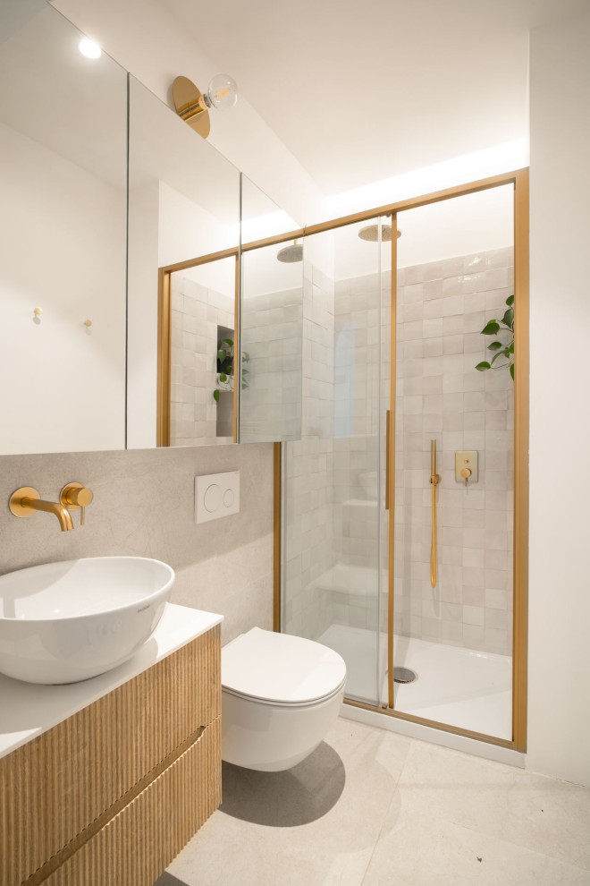 This is an example of a small traditional 3/4 bathroom in Milan with raised-panel cabinets, light wood cabinets, a wall-mount toilet, beige tile, cement tile, beige walls, ceramic floors, a vessel sink, solid surface benchtops, white floor, a sliding shower screen, white benchtops, a niche, a single vanity and a freestanding vanity.