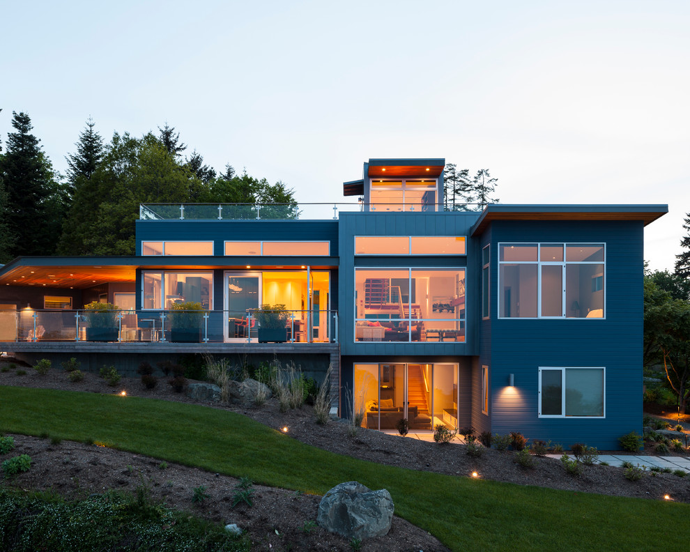 Mid-sized contemporary three-storey grey house exterior in Seattle with concrete fiberboard siding, a flat roof and a metal roof.