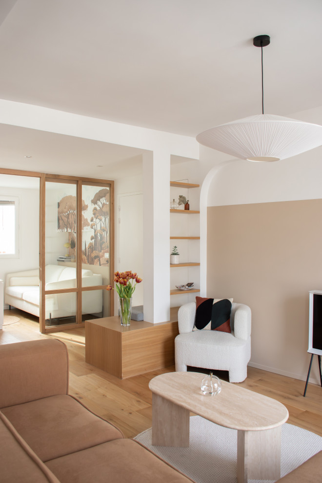 Стильный дизайн: гостиная комната с бежевыми стенами, светлым паркетным полом и отдельно стоящим телевизором - последний тренд