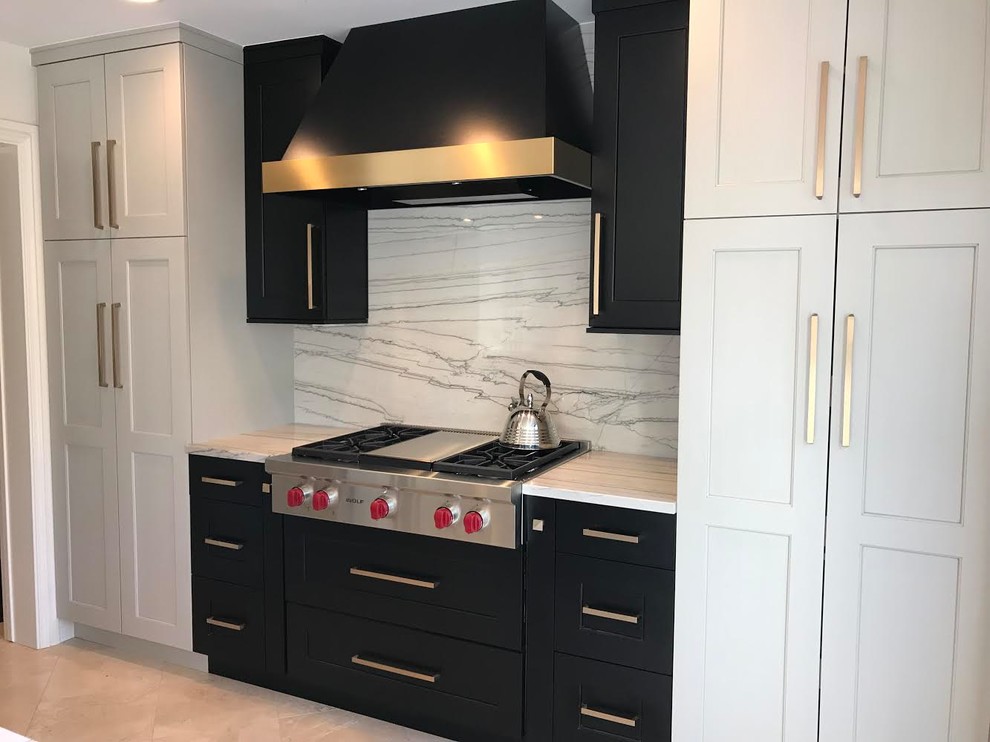 Design ideas for a large transitional l-shaped eat-in kitchen in Denver with an undermount sink, shaker cabinets, black cabinets, marble benchtops, white splashback, marble splashback, black appliances, limestone floors, with island, beige floor and white benchtop.