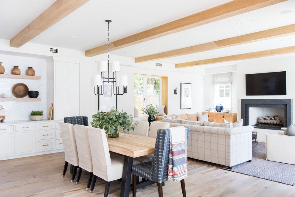 Inspiration for a beach style open plan dining in Orange County with white walls, light hardwood floors, a standard fireplace and beige floor.