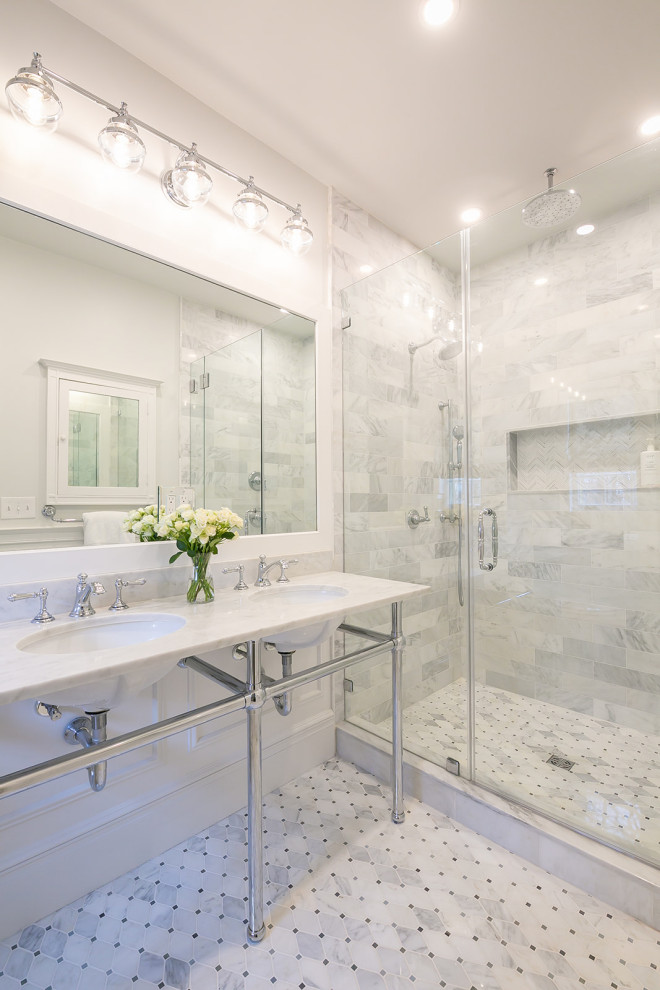 Design ideas for a traditional bathroom in Baltimore with white cabinets, a walk-in shower, a two-piece toilet, white tiles, marble tiles, white walls, marble flooring, a pedestal sink, marble worktops, white floors, a hinged door, white worktops, a wall niche, double sinks and wainscoting.