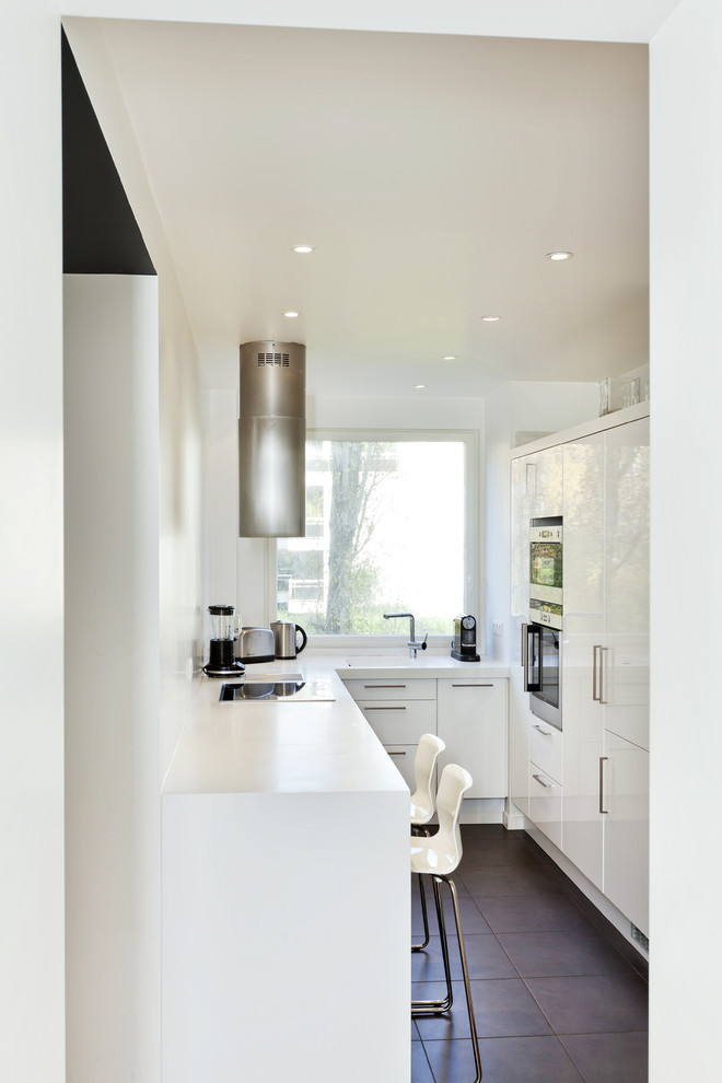 This is an example of a small contemporary u-shaped separate kitchen in Paris with stainless steel appliances, ceramic floors, no island, flat-panel cabinets and white cabinets.