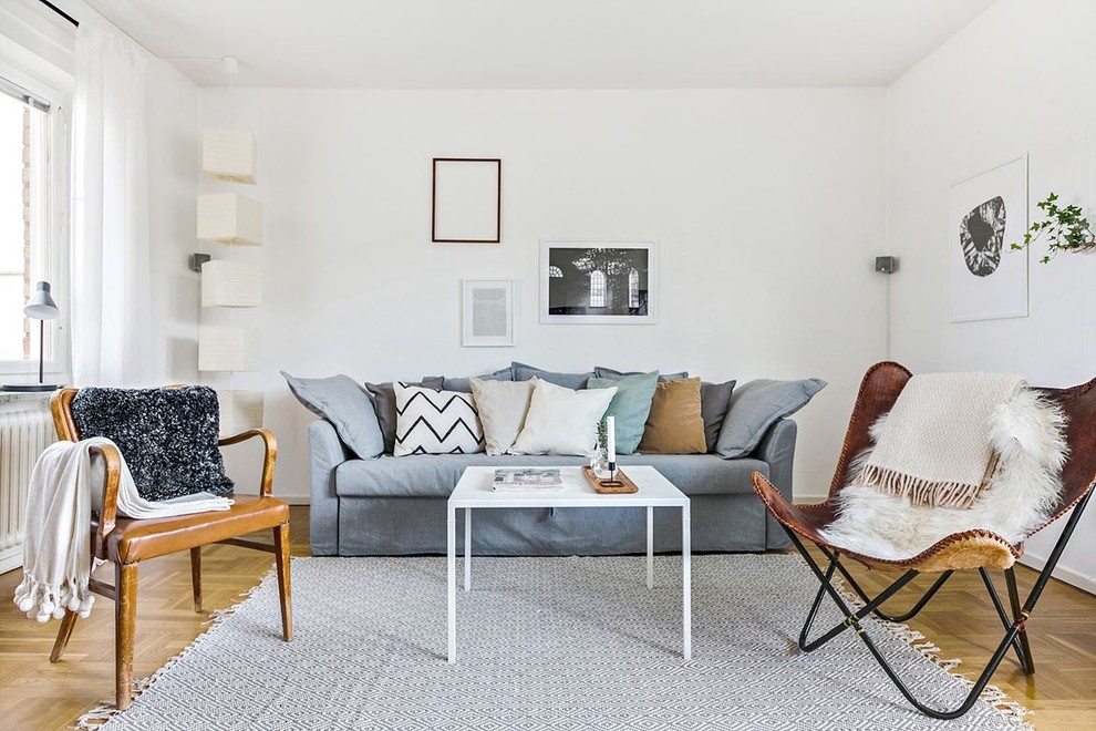 This is an example of a scandinavian living room in Stockholm with white walls, light hardwood floors and beige floor.