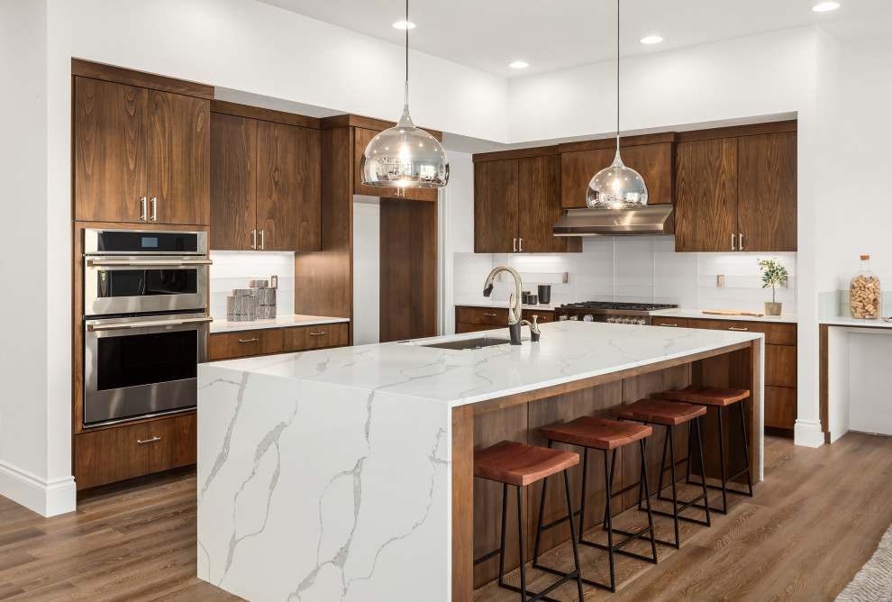 Small midcentury l-shaped eat-in kitchen in New York with an undermount sink, flat-panel cabinets, dark wood cabinets, quartz benchtops, multi-coloured splashback, engineered quartz splashback, stainless steel appliances, light hardwood floors, with island, brown floor and white benchtop.
