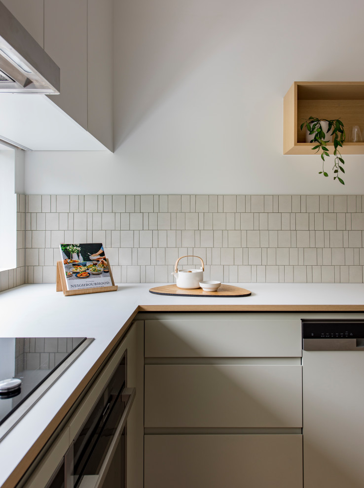 Photo of a contemporary u-shaped kitchen/diner in Melbourne with a double-bowl sink, flat-panel cabinets, beige cabinets, composite countertops, beige splashback, ceramic splashback, stainless steel appliances, medium hardwood flooring, an island, brown floors and white worktops.