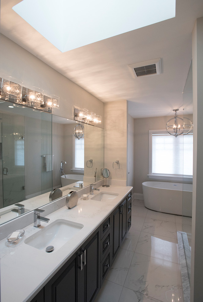 Photo of a mid-sized contemporary master bathroom in Toronto with raised-panel cabinets, black cabinets, a freestanding tub, a corner shower, white tile, marble, white walls, marble floors, an undermount sink, white floor, a hinged shower door and white benchtops.